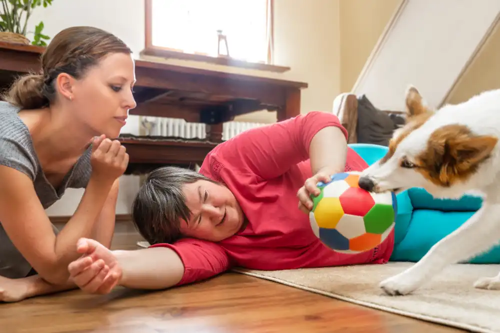 Woman laying on the floor playing with a trained care dog